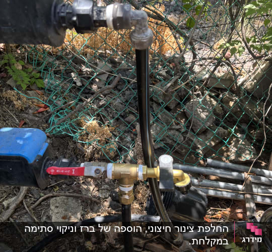 צנרת ומחברים בגינה עם צמחייה ברקע